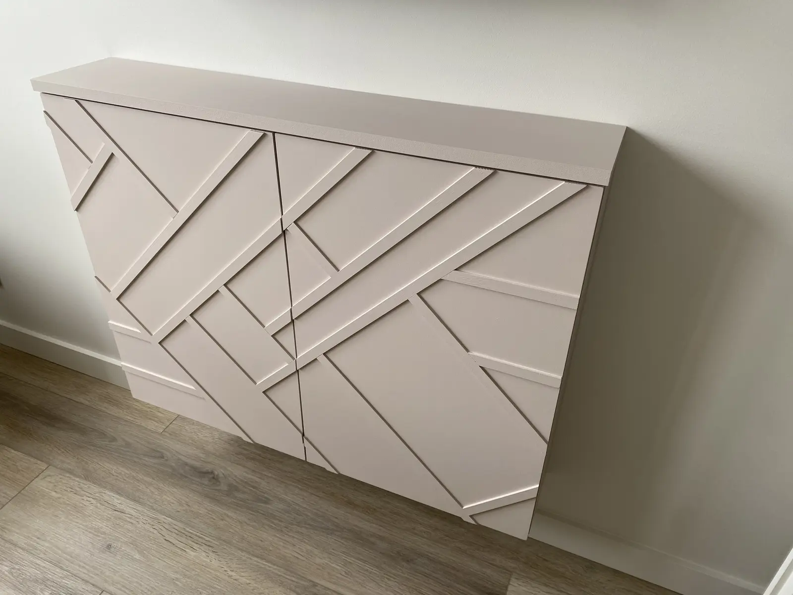 Placard mural fait sur mesure, peint en couleur rose pâle, avec un design géométrique composé de lignes et de formes rectangulaires.